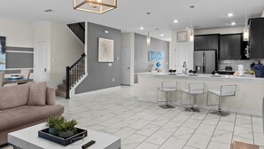 A modern kitchen with a central island, bar stools, and a built-in refrigerator.
