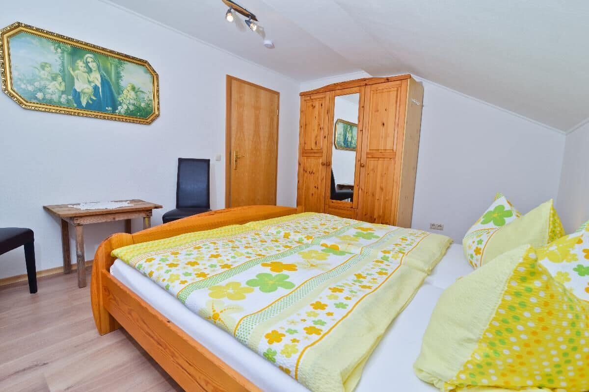 Ein Schlafzimmer mit einem hölzernen Bett, einem Schreibtisch, einem Stuhl und einem Kleiderschrank.