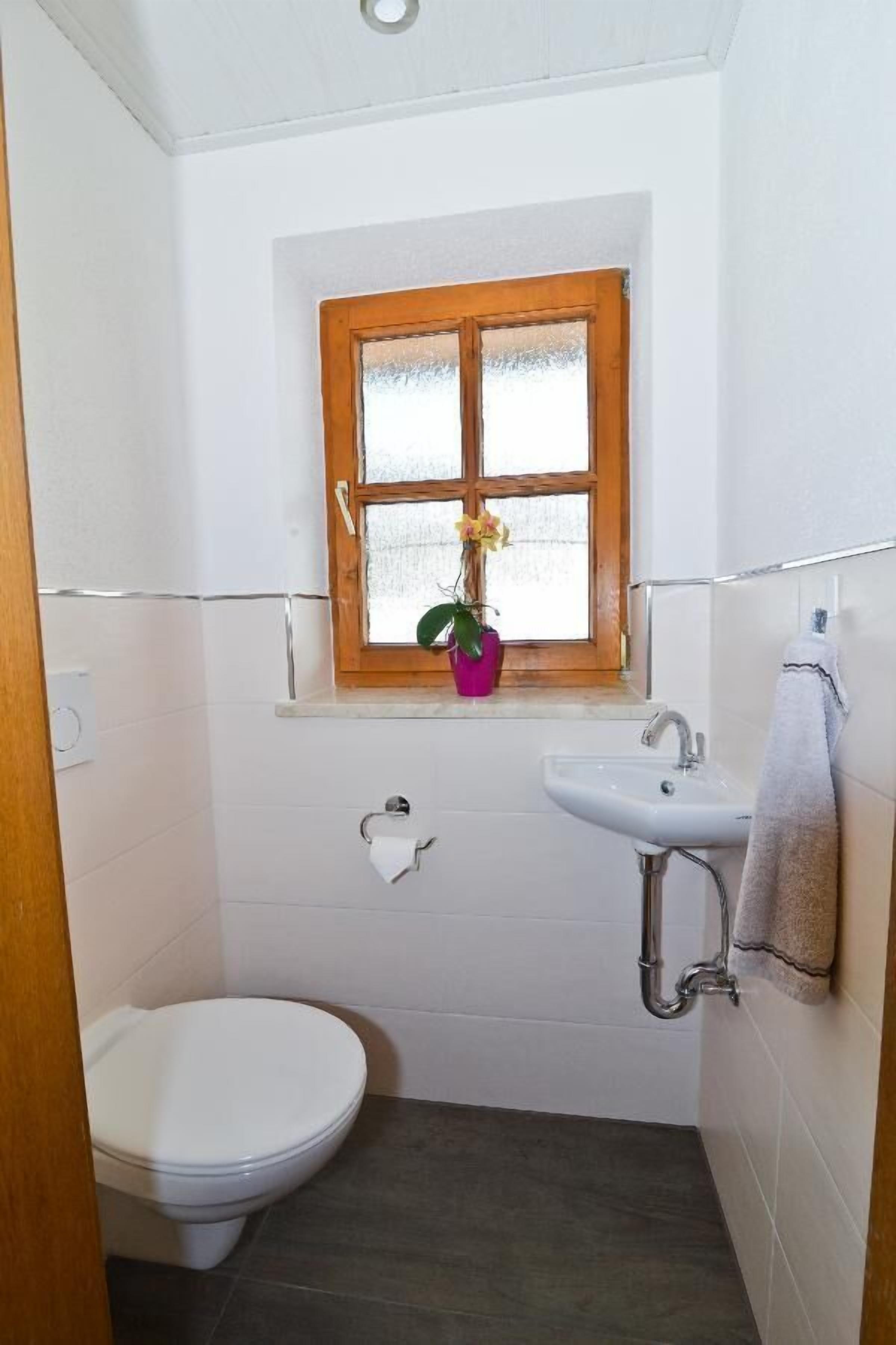 Ein kleines Badezimmer mit Toilette, Waschbecken und Fenster.