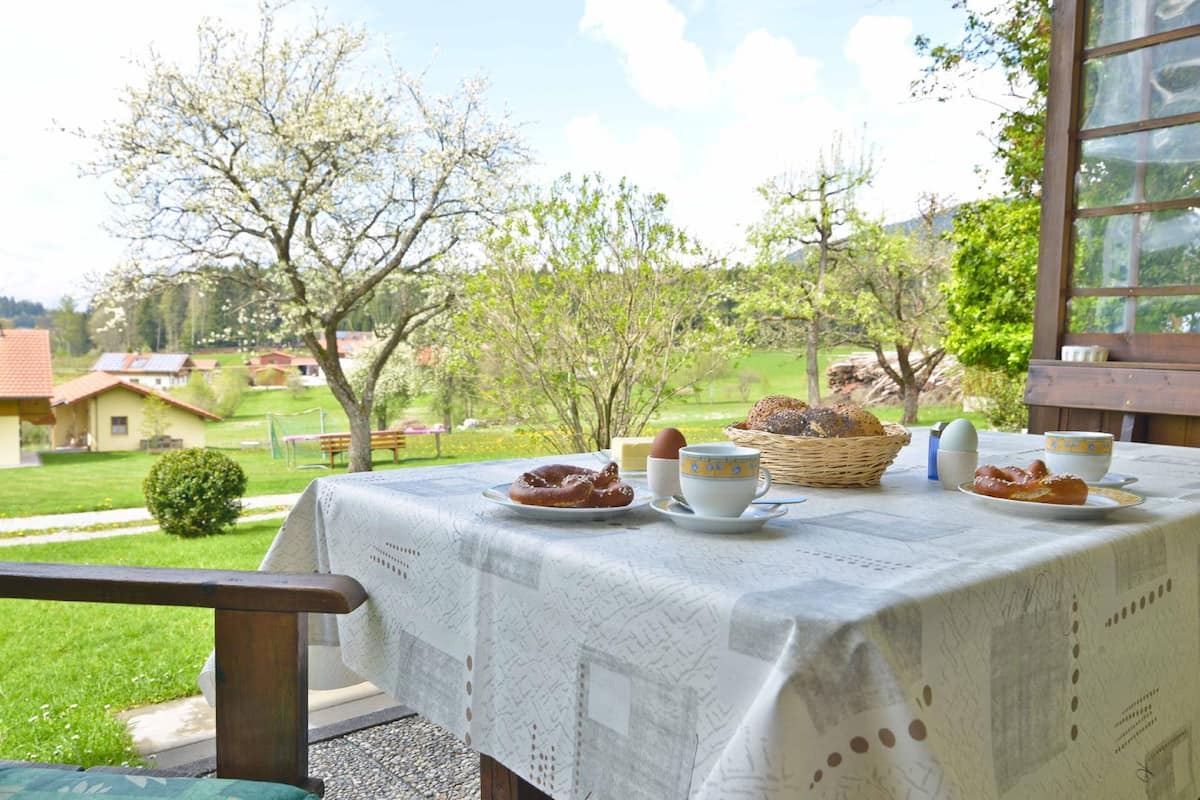 Ein Tisch im Freien mit Frühstücksgebäck, Blick auf eine grüne Landschaft und einem Holztischgestell.