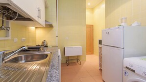 Uma cozinha compacta com pia, fogão, geladeira e máquina de lavar.
