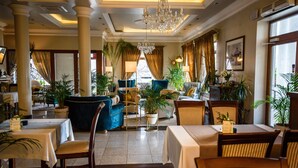 Un hall d’hôtel bien éclairé, agrémenté d’un lustre, de fauteuils confortables et de plantes en pot.