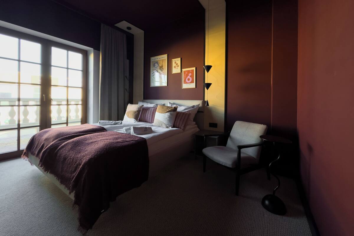 Habitación de hotel con una cama grande, una silla, un escritorio y ventana con vistas.