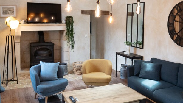 A cozy living room with a fireplace, sofas, a coffee table, and hanging light fixtures. - Charming house, quiet, in the heart of the Parc du Perche, 50m from the forest (CONDEAU)