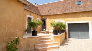 A courtyard with steps leading to a door, potted plants, and a garage. - Charming house, quiet, in the heart of the Parc du Perche, 50m from the forest (CONDEAU)