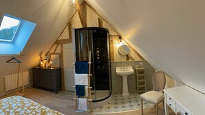 A cozy attic bedroom with a skylight, a shower, a bed with floral bedding, and a small desk. - Charming house, quiet, in the heart of the Parc du Perche, 50m from the forest (CONDEAU)