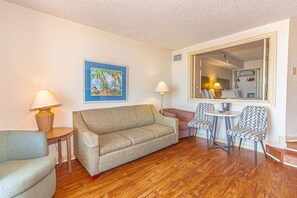A living room with a sofa, two chairs, a small table, and a painting on the wall. - Beach Colony 403 (Myrtle Beach)