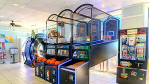 Une salle d’arcade proposant des jeux vidéo sur le thème du basketball, un panier de basketball et une porte donnant accès à des prix.
