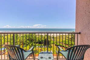 A balcony with a view of the beach, two chairs, and a table. - Beach Colony 403 (Myrtle Beach)