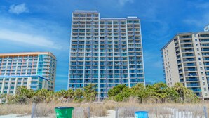 Un hôtel de grande hauteur, avec de nombreux étages, des balcons et une vue sur la plage.