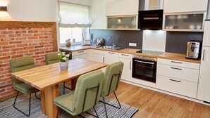 Une cuisine moderne avec une table et des chaises en bois, un mur d’accent en briques et des appareils électroménagers intégrés.