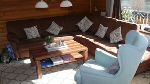 A cozy living room with a brown sectional sofa, a light blue armchair, and a wooden coffee table with decorative items.