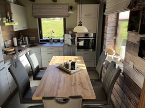 A modern kitchen with a wooden table, built-in appliances, and a view of the outdoors. - FeWo Falk 26 OG am See (Arrach)