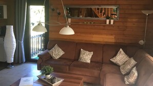 A cozy living room with a brown sofa, a wooden coffee table, and a hanging light fixture.