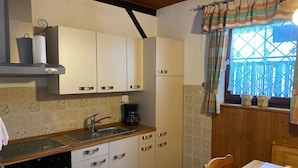 Una cocina compacta con armarios blancos, horno integrado, fregadero y ventana con vistas.