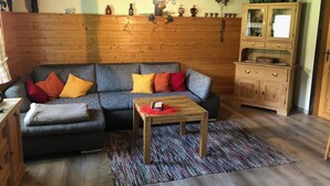 Un salón acogedor con un sofá seccional, una mesita de centro y un mueble de madera.