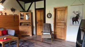 Un salón acogedor con un sofá de madera, un sillón estampado, una mesa de centro y una chimenea.
