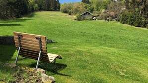 Un campo cubierto de hierba con un banco de madera y un muro de piedra.