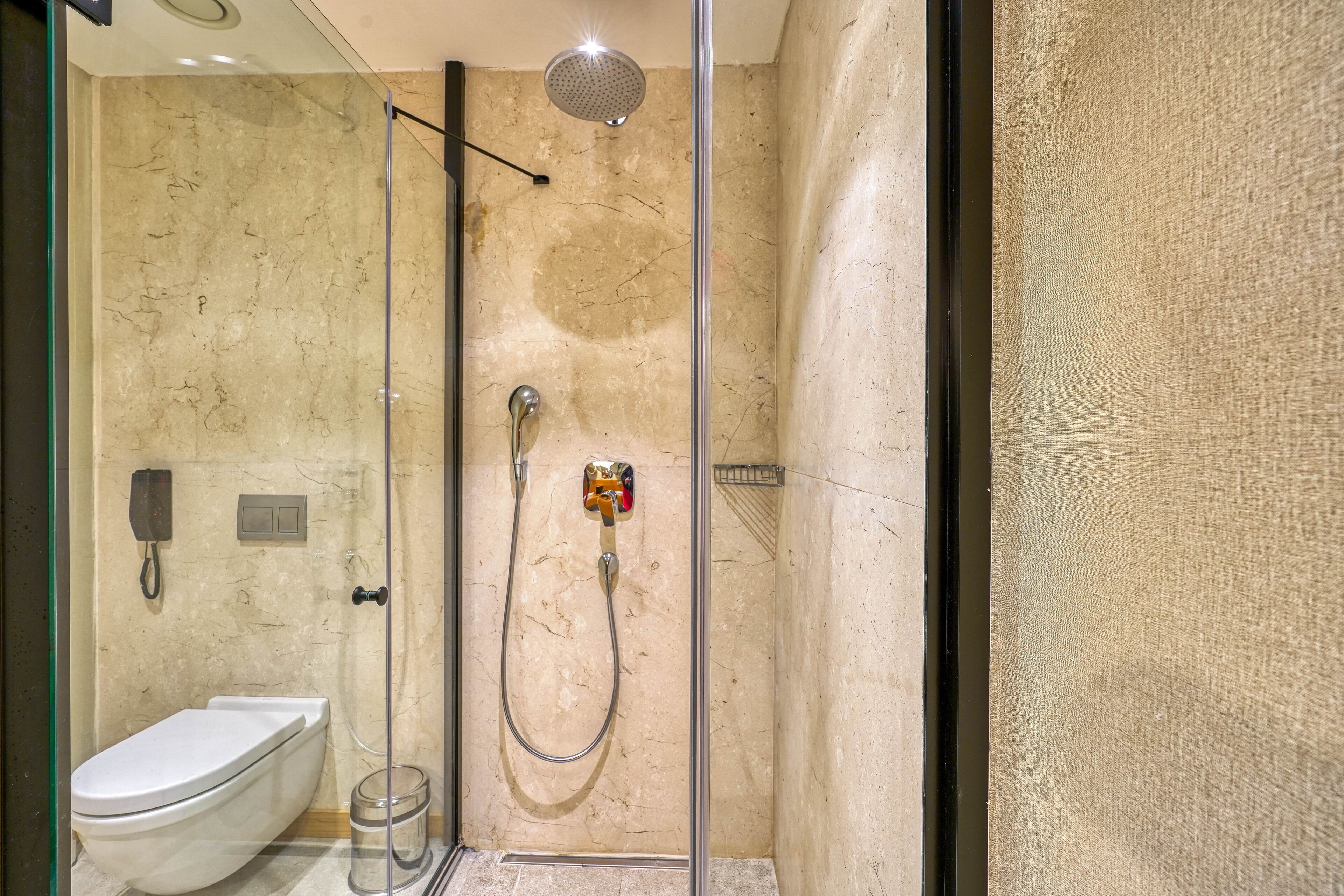 Un baño moderno con ducha de vidrio, inodoro y pared de mármol.