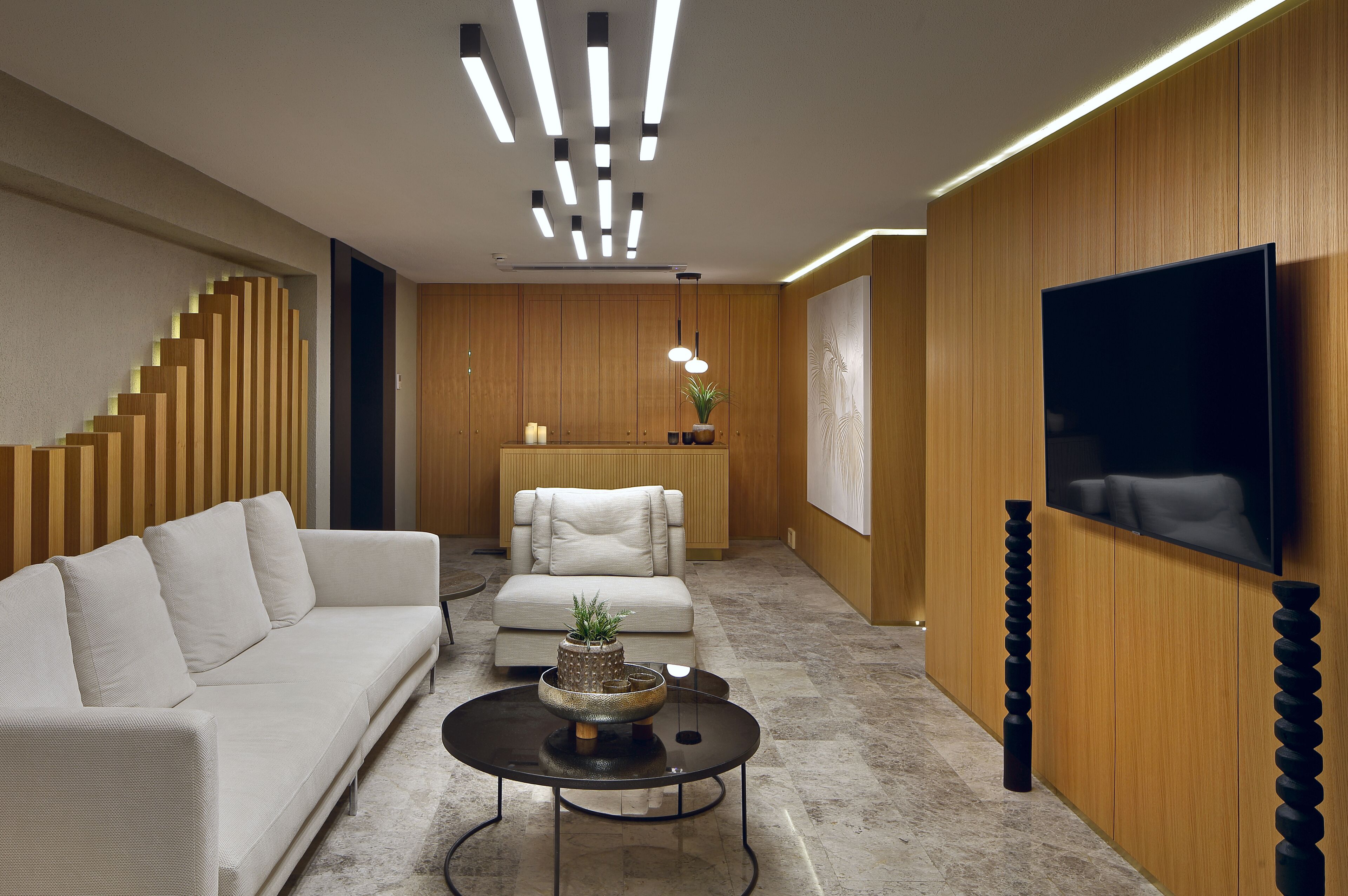 A modern living room with a sofa, a coffee table, and a TV mounted on the wall.