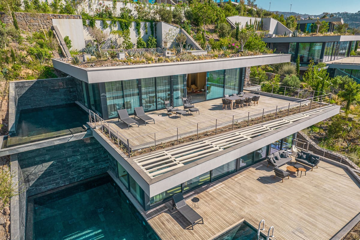 A modern building with a rooftop pool area, glass walls, and a wooden deck.