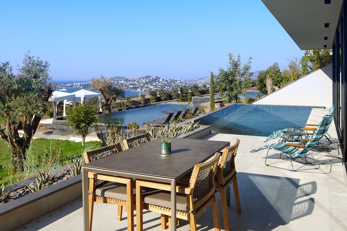 A terrace with a pool, outdoor seating, and a view of the sea.