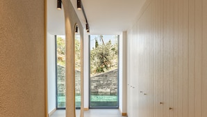 Un couloir avec un mur en pierre, un plancher en bois et une vue sur un jardin extérieur.