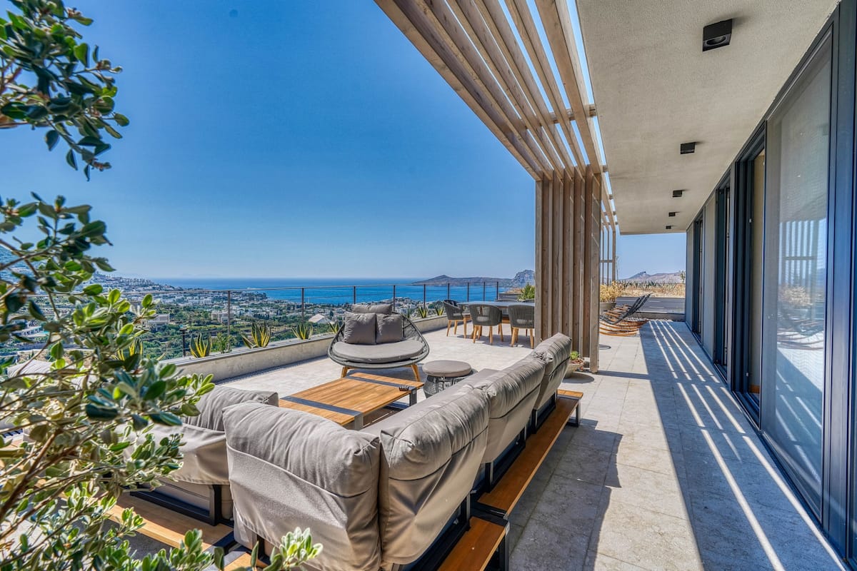 A modern outdoor seating area with a view of the ocean and cityscape.