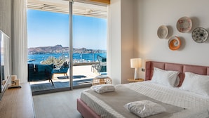 Une chambre d’hôtel avec un grand lit, une vue sur la mer et un balcon équipé de chaises.