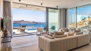 Un salon moderne avec un grand canapé, une table basse et une vue sur la mer.