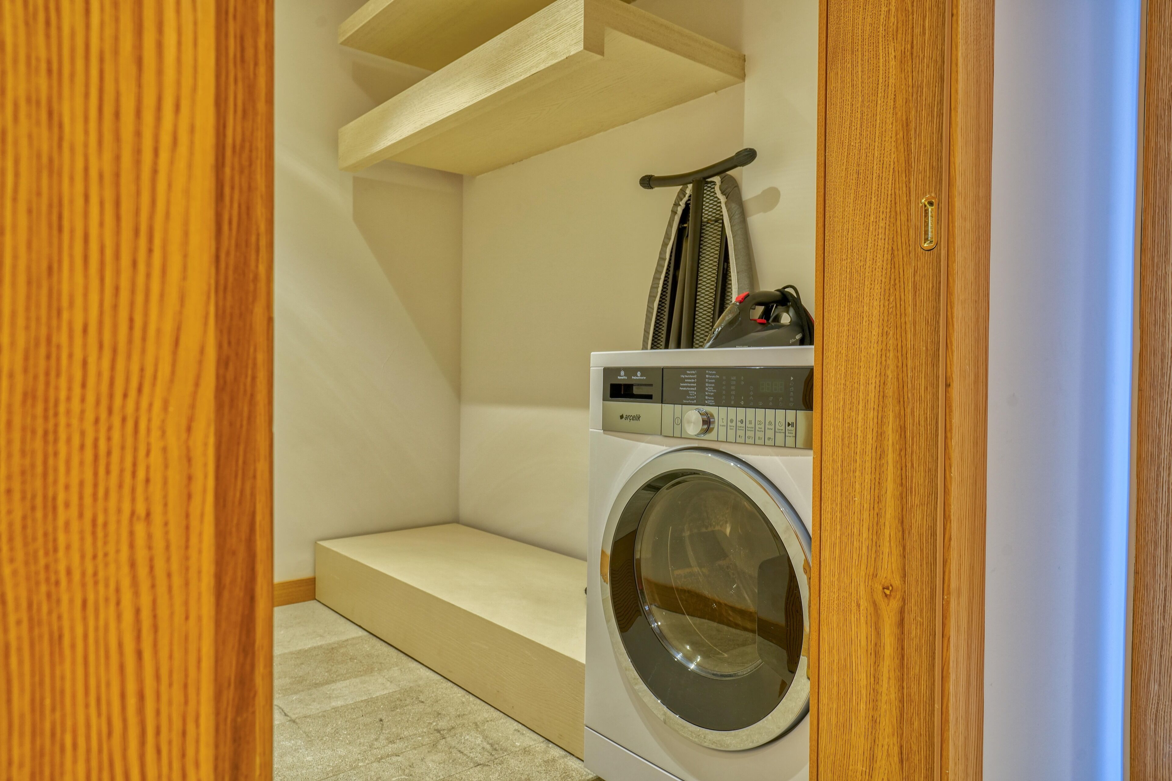 Een wasruimte met een wasmachine en droger, houten treden en een handdoekhouder.