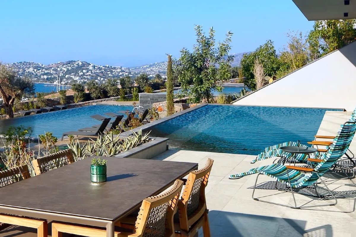 A poolside area with a table, chairs, and lounge chairs.