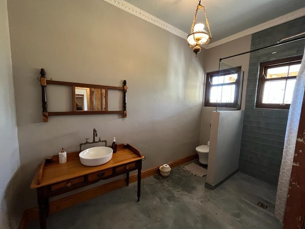 A bathroom with a wooden vanity, a large mirror, a white sink, a toilet, and a shower area.