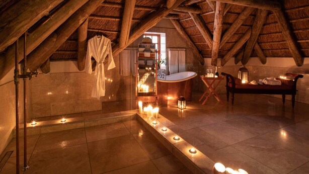 A spa room with a bathtub, candles, and a robe hanging on a rack. - Magic Hills - Ilanga Manor House (Ikwezi)