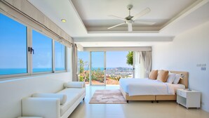 Een moderne slaapkamer met een groot bed, een bank en uitzicht op zee.