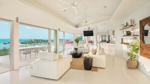 Een ruime woonkamer met een grote schuifpui die leidt naar een balkon met uitzicht op zee.