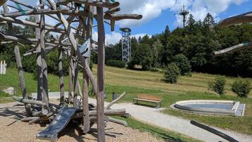Un parque infantil con tobogán, banco y fuente circular.