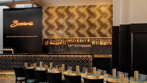 A bar area with a neon sign reading "Brovaria," a wall of illuminated dots, and a neatly arranged seating area with tables and chairs. - Brovaria (Poznan)