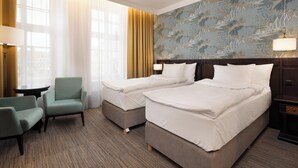A hotel room with two beds, a small table, a chair, and a lamp. - Brovaria (Poznan)