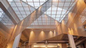 A spacious interior with a high ceiling and a large, geometric, mesh-like structure. - Brovaria (Poznan)