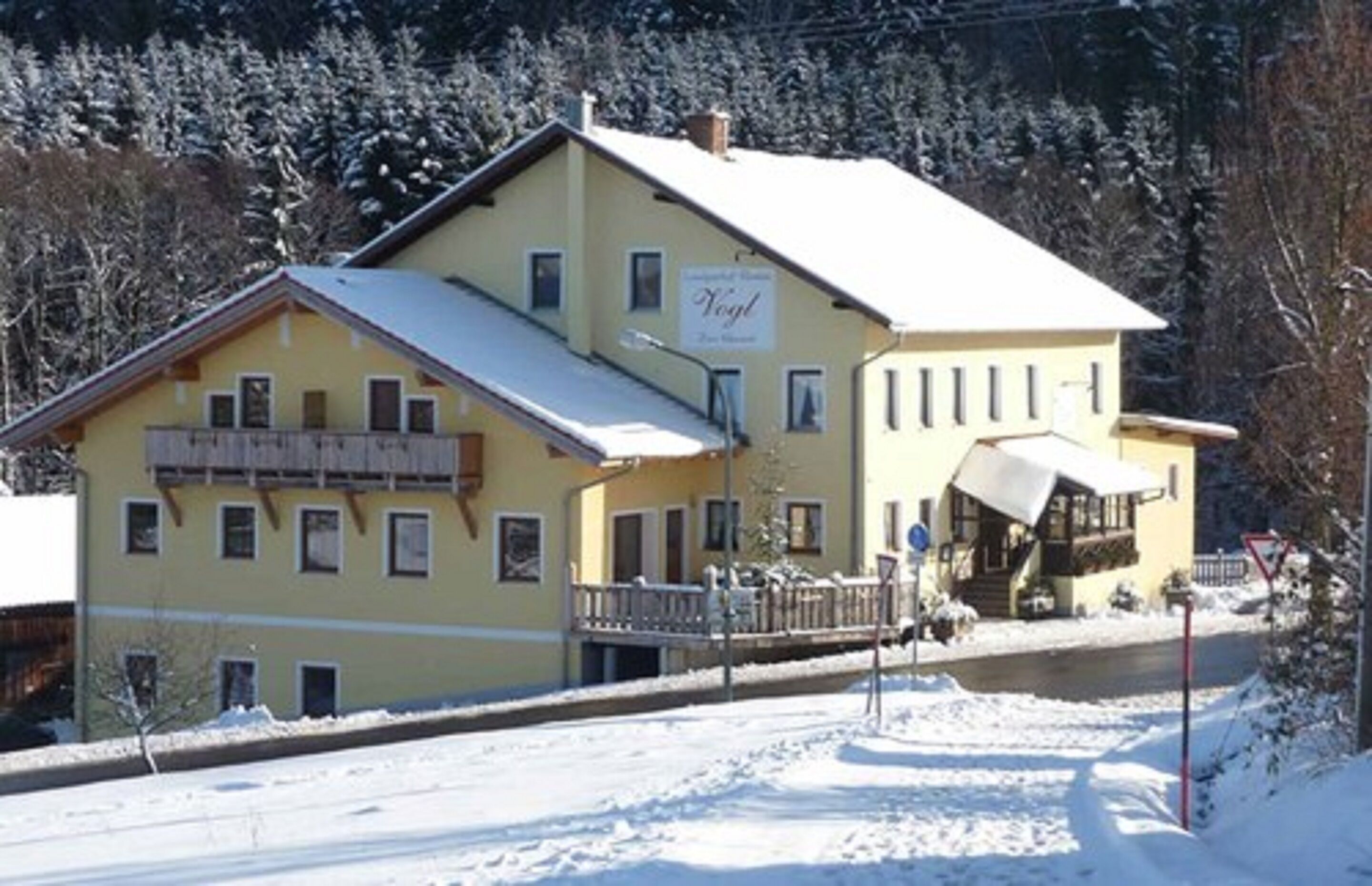 Ein zweistöckiges Gebäude mit einem mit Schnee bedeckten Dach und einem Schild mit der Aufschrift "Vogel".