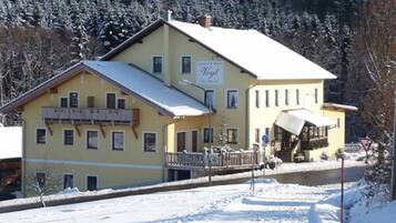 Ein zweistöckiges Gebäude mit einem mit Schnee bedeckten Dach und einem Schild mit der Aufschrift "Vogel".