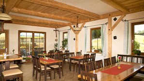 A dining area with wooden tables and chairs, large windows, and a high wooden ceiling. - Landgasthof Vogl - Zum Klement (Neukirchen Beim Heiligen Blut)