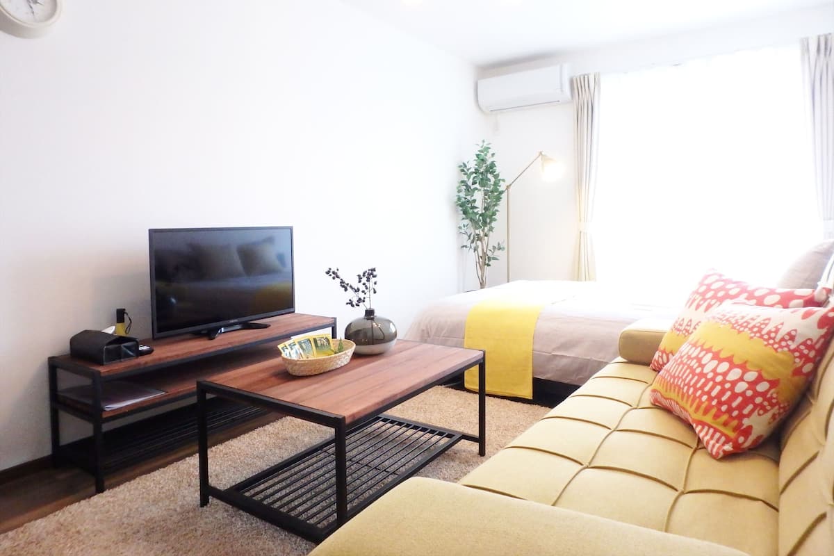 Una sala de estar moderna con una televisión de pantalla plana, una mesa de centro, un sofá y una planta.