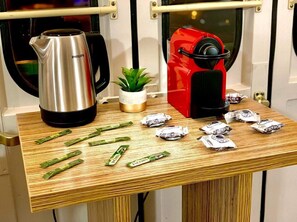 A kitchen counter with a coffee maker, a kettle, and several packets of coffee. - Übernachtung im nostalgischen Bahnwaggon (Bogen)