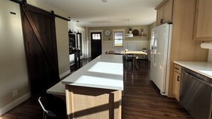 A kitchen with a central island, wooden cabinets, a refrigerator, and a dining area with chairs. - Heart of Houghton! Trails, Shopping & More! (Dodgeville)