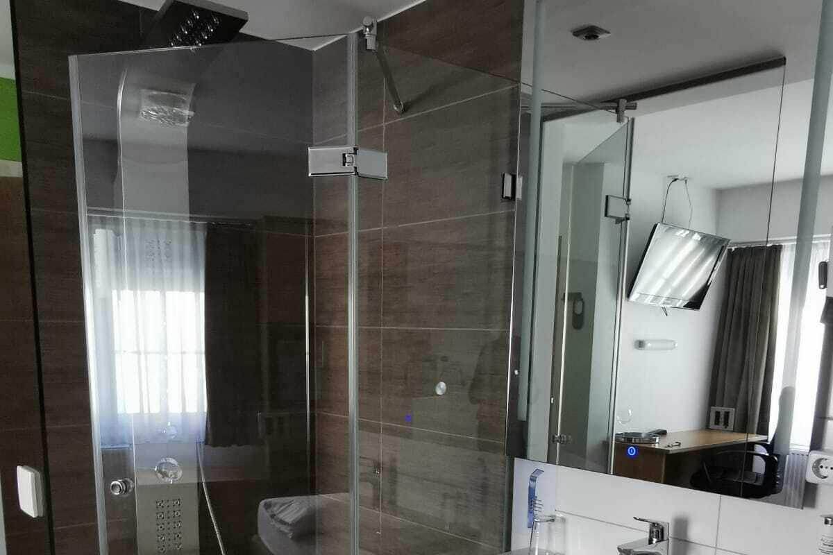 A modern bathroom with a glass-enclosed shower, a white sink, and a small white stool.
