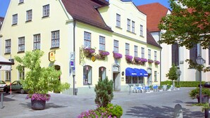 En bygning med gul facade, mange vinduer og rødt tag.