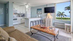 Une cuisine moderne avec des meubles blancs, un îlot central et un coin repas comprenant une table et des chaises.