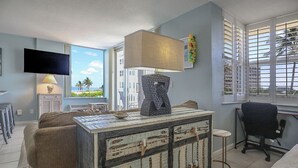 Une chambre moderne dotée d’une grande fenêtre, d’un téléviseur à écran plat, d’une lampe originale et d’une commode au style rustique.